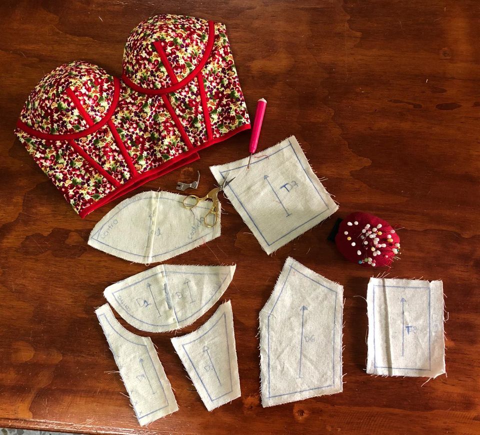 Piezas de patrón de corsetería y copas bordadas sobre una mesa de trabajo