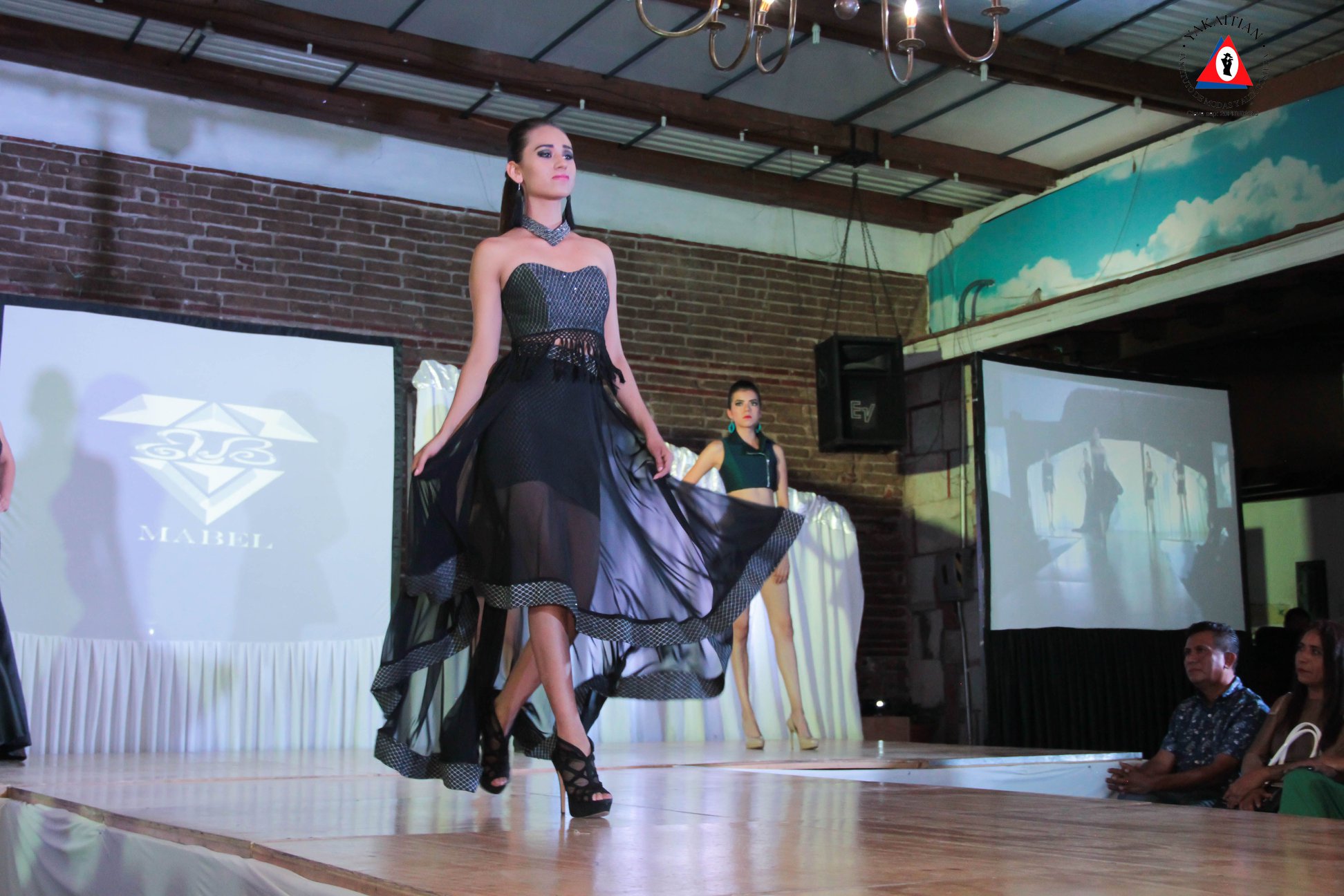 Modelo caminando por la pasarela con un vestido negro de noche
