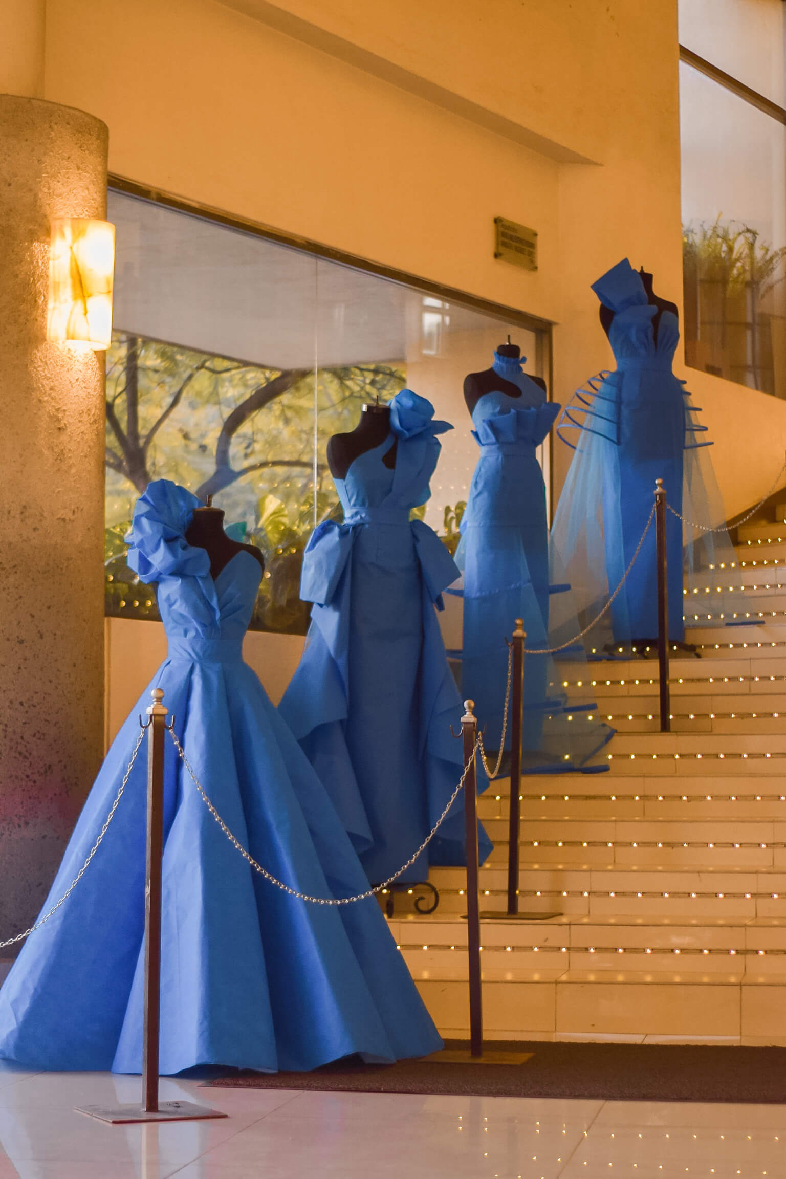 Vestidos de noche en exhibición sobre maniquíes en la escalinata de la escuela